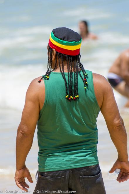 Imagem de um moço de costas com chapéu colorido e rastafare.